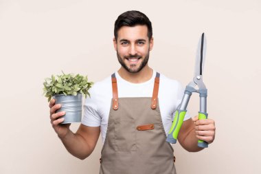 Bahçıvan arka planda budama makası tutuyor.
