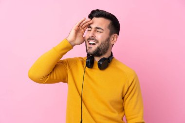 Kulaklıkları ve pembe arka planı olan genç yakışıklı bir adam bir şey fark etti ve çözümü arıyor.