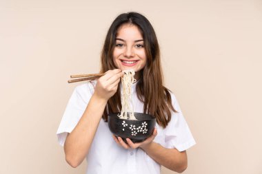 Bir kase erişteyi izole edilmiş arka planda tutan bir kız.