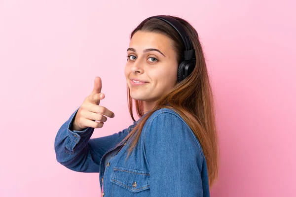 Ragazza adolescente ascoltando musica oltre isolato muro rosa — Foto Stock