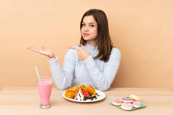 Chica Adolescente Comiendo Gofres Aislados Sobre Fondo Beige Sosteniendo Espacio — Foto de Stock