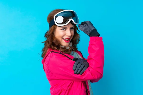 Narciarka Okularami Snowboardowymi Odizolowanej Niebieskiej Ścianie Robi Silny Gest — Zdjęcie stockowe