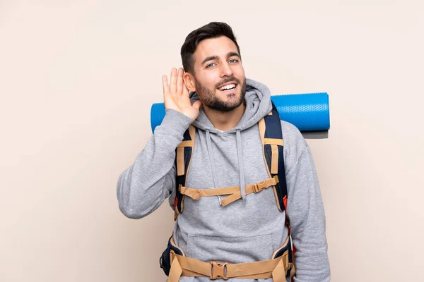 Joven Montañero Con Una Gran Mochila Sobre Fondo Aislado Escuchando —  Fotos de Stock