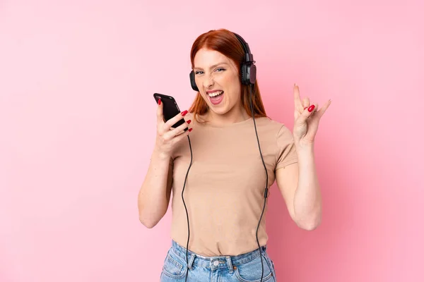 Young Redhead Woman Isolated Pink Background Using Mobile Headphones Singing — Stock Photo, Image