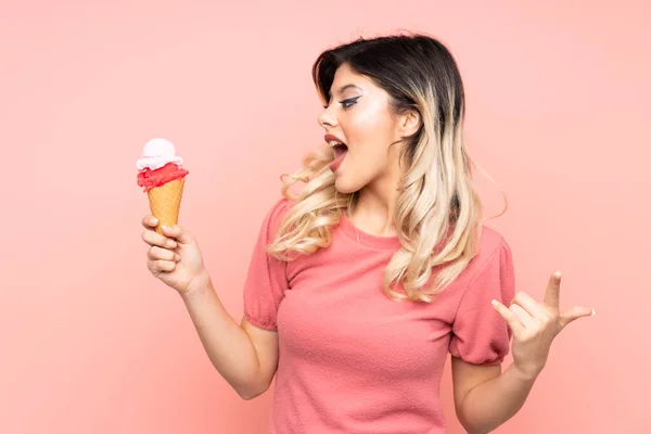 분홍색 배경에 고립된 아이스크림을 소녀가 나머지 손가락으로 가리키는 — 스톡 사진