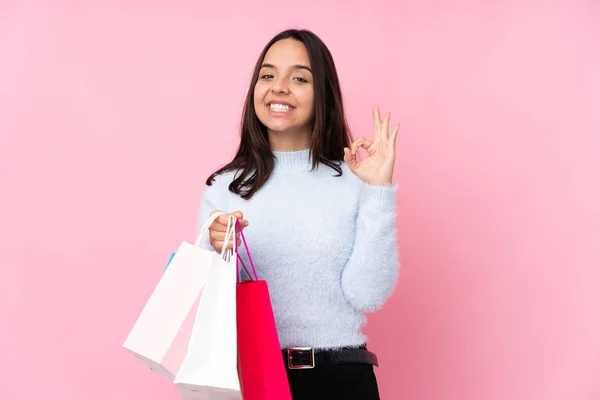 若いです女性とともにショッピングバッグ以上隔離されたピンクの背景ショーOk Signとともに指 — ストック写真