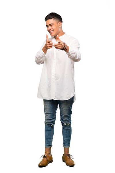 A full-length shot of a Young man pointing to the front and smiling over isolated white background