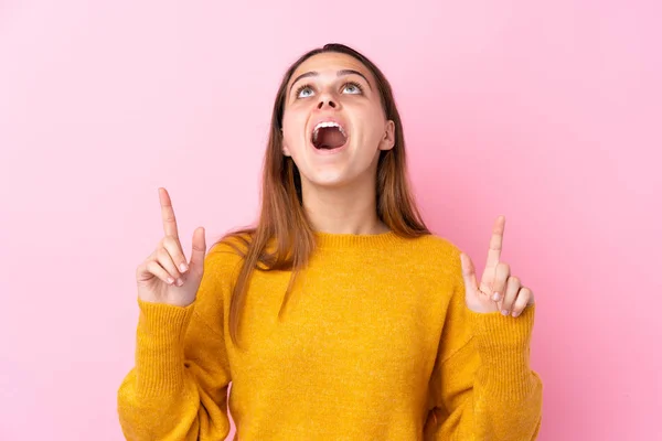 Ragazza Adolescente Con Maglione Giallo Sfondo Rosa Isolato Sorpreso Indicando — Foto Stock