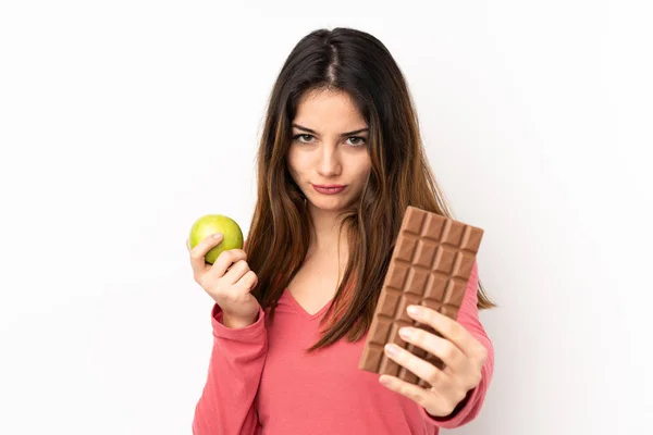 Rózsaszín Alapon Izolált Fiatal Kaukázusi Egyik Kezében Csokoládétablettával Másikban Almával — Stock Fotó