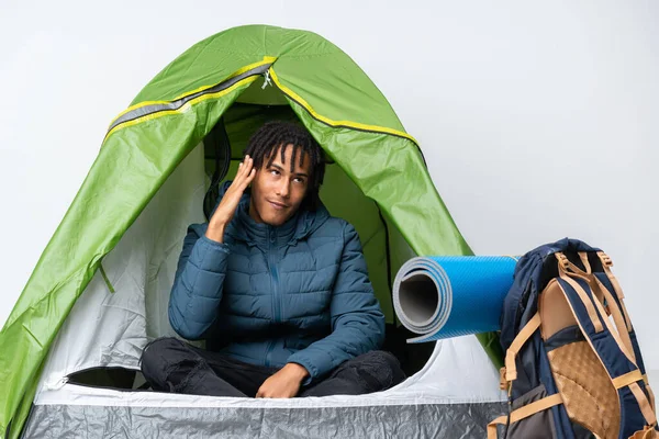 Young african american man inside a camping green tent with tired and sick expression