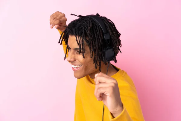 Fiatal afro-amerikai férfi zenét hallgat izolált rózsaszín wa — Stock Fotó