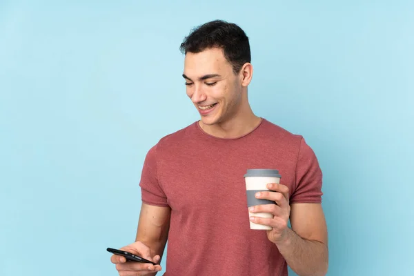 Jovem Caucasiano Bonito Homem Isolado Fundo Azul Segurando Café Para — Fotografia de Stock