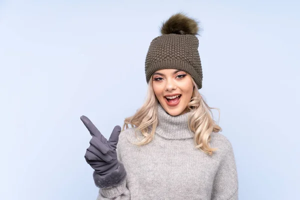 Giovane Ragazza Adolescente Con Cappello Invernale Sfondo Blu Isolato Puntando — Foto Stock