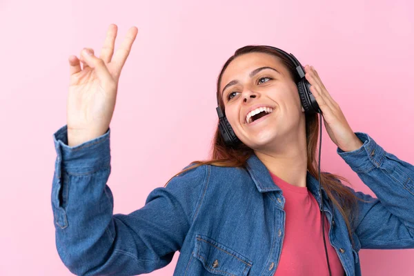 Teenager girl listening music over isolated pink wall — Stock Photo, Image