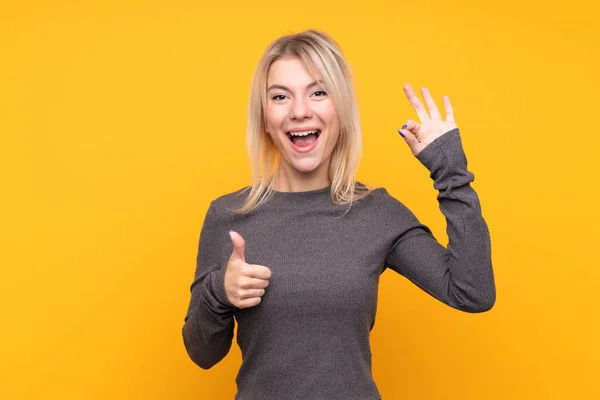 Mujer Rubia Joven Sobre Fondo Amarillo Aislado Mostrando Signo Pulgar — Foto de Stock