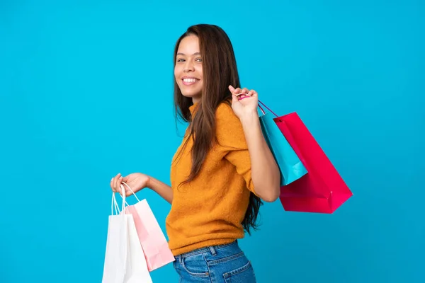 Joven Brasileña Sobre Fondo Azul Aislado Sosteniendo Bolsas Compras Sonriendo —  Fotos de Stock