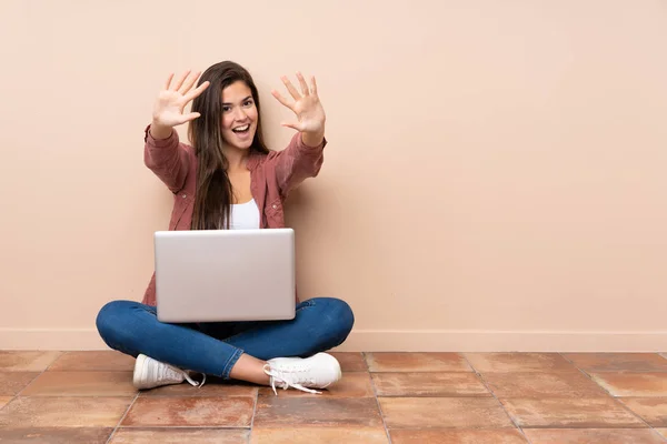 十几岁的女学生坐在地板上 手里拿着笔记本电脑 手里拿着十根手指 — 图库照片