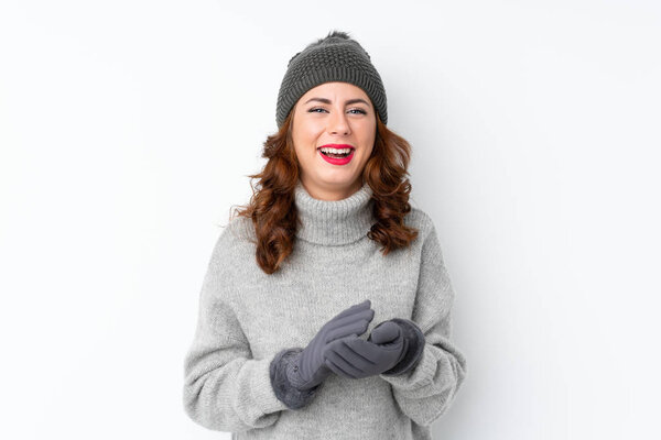 Young Russian woman with winter hat over isolated white background applauding