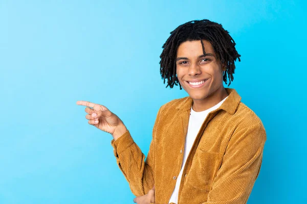 年轻的非裔美国人 身穿灯芯绒夹克 蓝色背景 手指指向侧面 — 图库照片