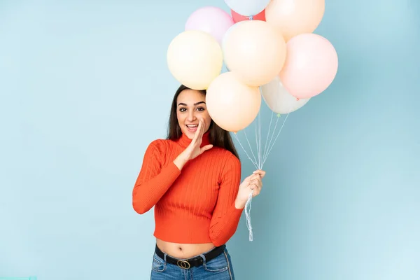 Junge Frau Fängt Viele Luftballons Isoliert Auf Blauem Hintergrund Und — Stockfoto