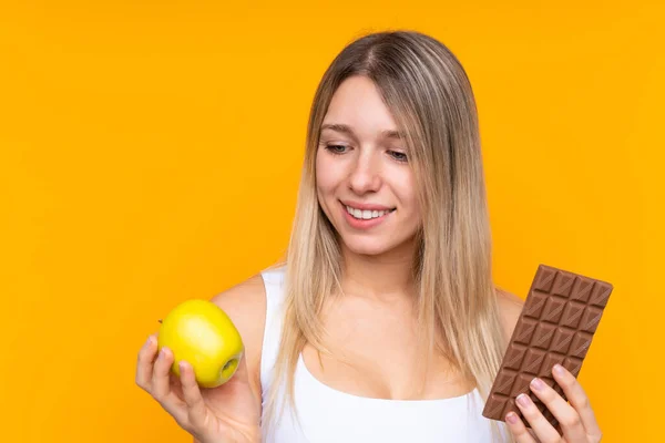 Jonge Blonde Vrouw Geïsoleerde Blauwe Achtergrond Nemen Van Een Chocolade — Stockfoto