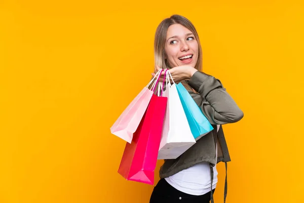 Young Blonde Woman Isolated Yellow Background Holding Shopping Bags Smiling — 스톡 사진