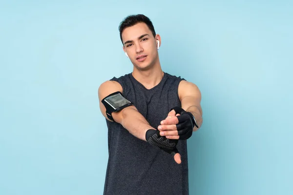 Joven Deportista Sobre Aislado Sobre Fondo Azul Brazo Estiramiento — Foto de Stock