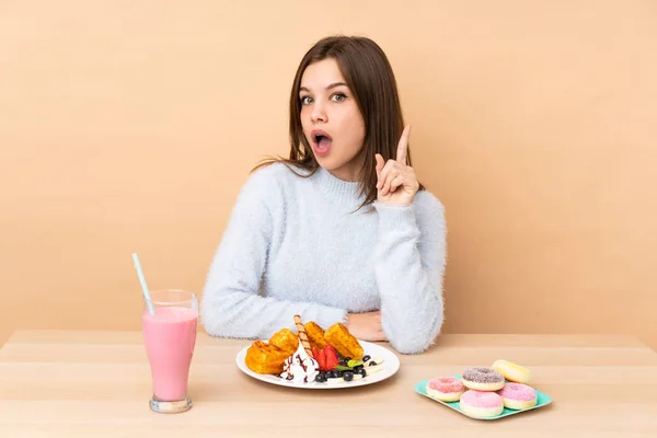 Chica Adolescente Comiendo Gofres Aislados Sobre Fondo Beige Pensando Una —  Fotos de Stock