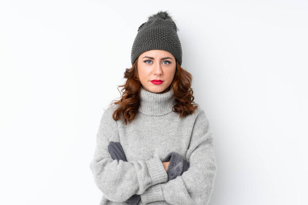 Young Russian woman with winter hat over isolated white background keeping arms crossed