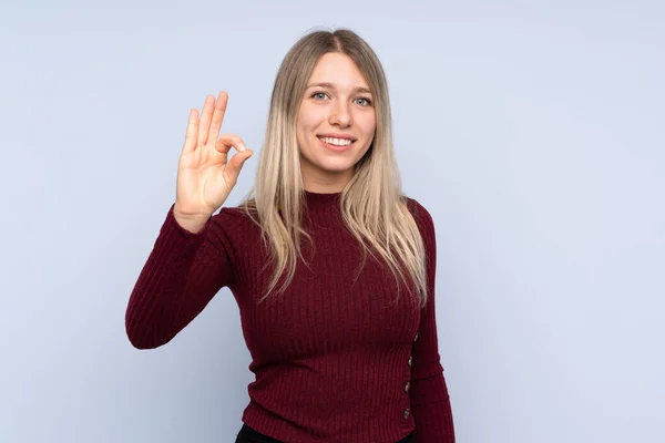Молода Блондинка Над Ізольованим Блакитним Тлом Показує Знак Пальцями — стокове фото