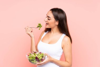 Pembe arka planda salata tutan beyaz bir kadın.