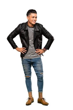 Kolları kalçasında poz veren ve izole edilmiş beyaz arka planda gülümseyen bir genç adam.
