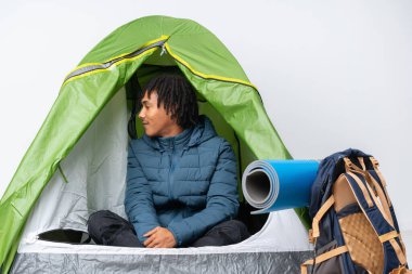 Genç Afro-Amerikan bir adam kamp içinde yeşil bir çadırda yan pozisyonda.