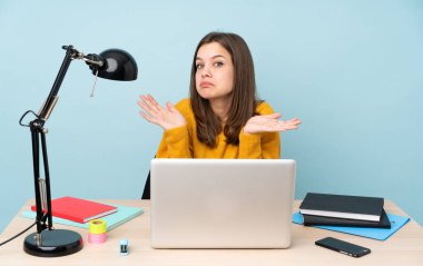 Öğrenci kız evinde mavi arka planda izole bir şekilde ders çalışıyor.