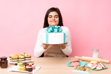 Soyutlanmış pembe arka planda bir masada büyük bir pasta şefi.