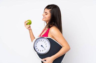 Tartı makinesi ve elmasıyla izole edilmiş beyaz arka planı olan genç bir kadın.