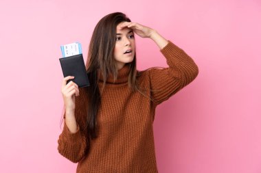 Pasaport ve uçak biletleriyle izole edilmiş pembe arka planı olan genç bir kız.