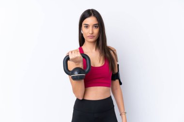 İzole edilmiş beyaz arka planda genç esmer kadın halter kaldırıyor, ağırlık kaldırıyor ve ön tarafa bakıyor.