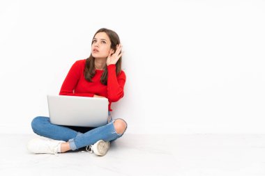 Polisle çalışan hassas kız beyaz arka planda izole edilmiş bir şekilde elini kulağına koyarak bir şeyler dinliyor.