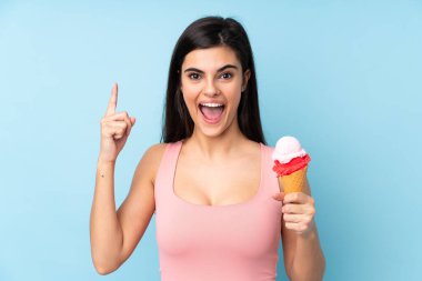 Kornet dondurması tutan genç bir kadın izole edilmiş mavi arka planda harika bir fikre işaret ediyor.