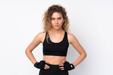 Beyaz arka planda izole edilmiş genç bir kadın kolları kalçasında poz veriyor.