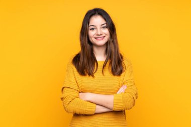 Sarı arka planda izole edilmiş, kolları çapraz ve ileriye bakan beyaz bir kadın.