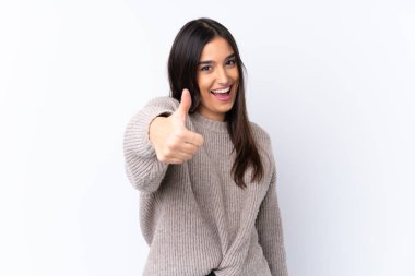 Genç esmer kadın izole edilmiş beyaz arka planda. Başparmakları havada. Çünkü iyi bir şey oldu.