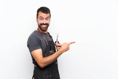 Önlüklü berber parmağını yana doğru gösteriyor.