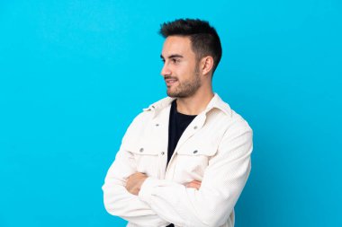Soyutlanmış mavi arka planda genç yakışıklı adam yan tarafa bakıyor.
