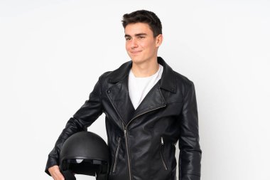 Beyaz arka planda izole edilmiş motosiklet kaskı tutan bir adam duruyor ve yan tarafa bakıyor.