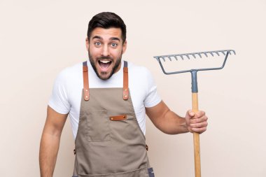 Bahçıvan arka planda bir tırmık tutuyor.