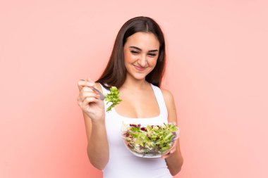 Pembe arka planda salata tutan beyaz bir kadın.
