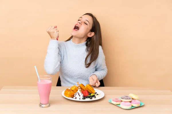 Chica Adolescente Comiendo Gofres Aislados Sobre Fondo Beige Celebrando Una —  Fotos de Stock