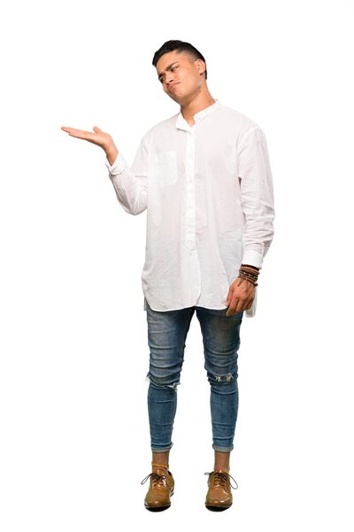 A full-length shot of a Young man holding copyspace with doubts over isolated white background